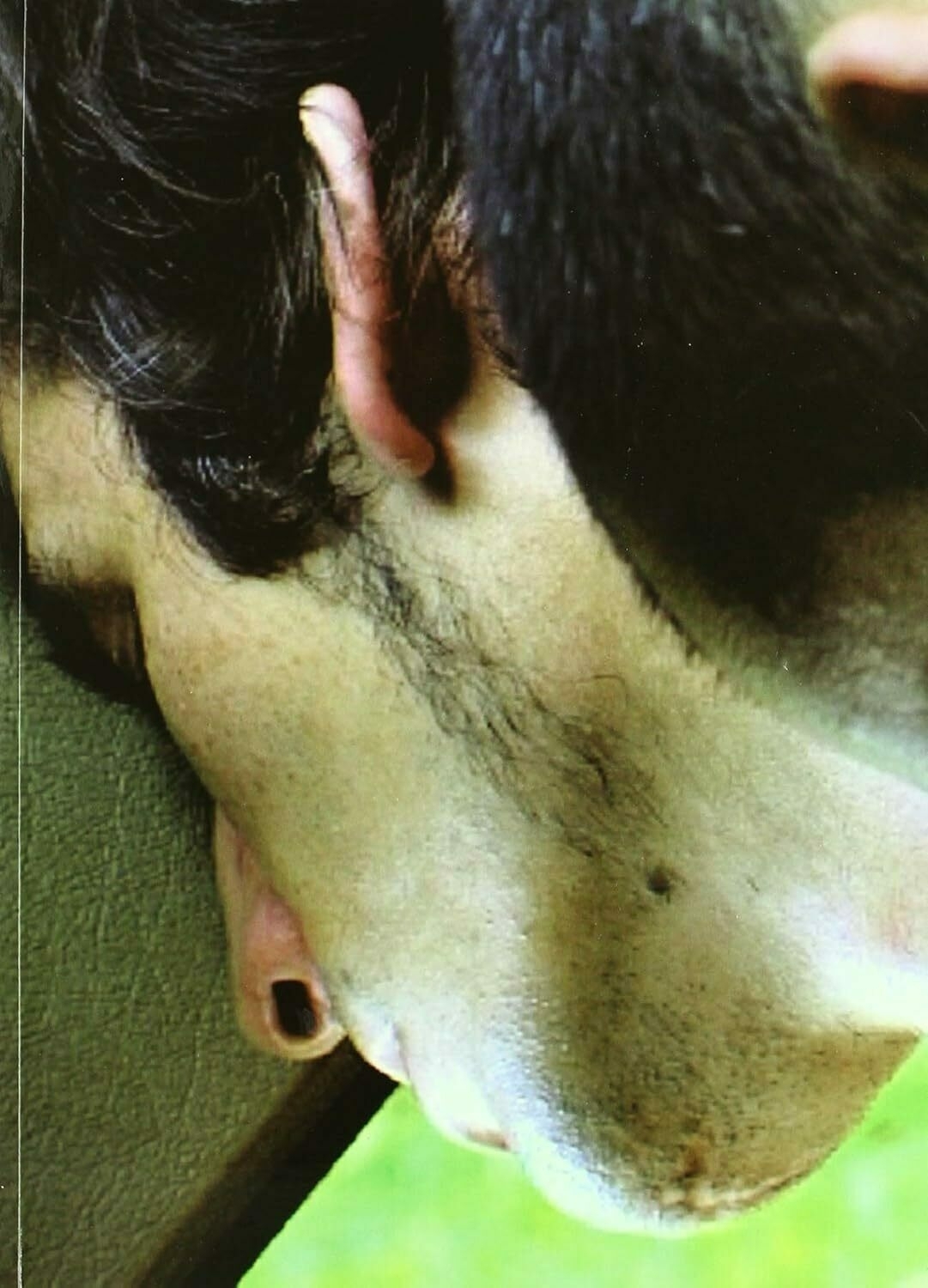 Auto-generated description: It's a close-up of a person leaning against a surface, with a visible ear and some facial hair.